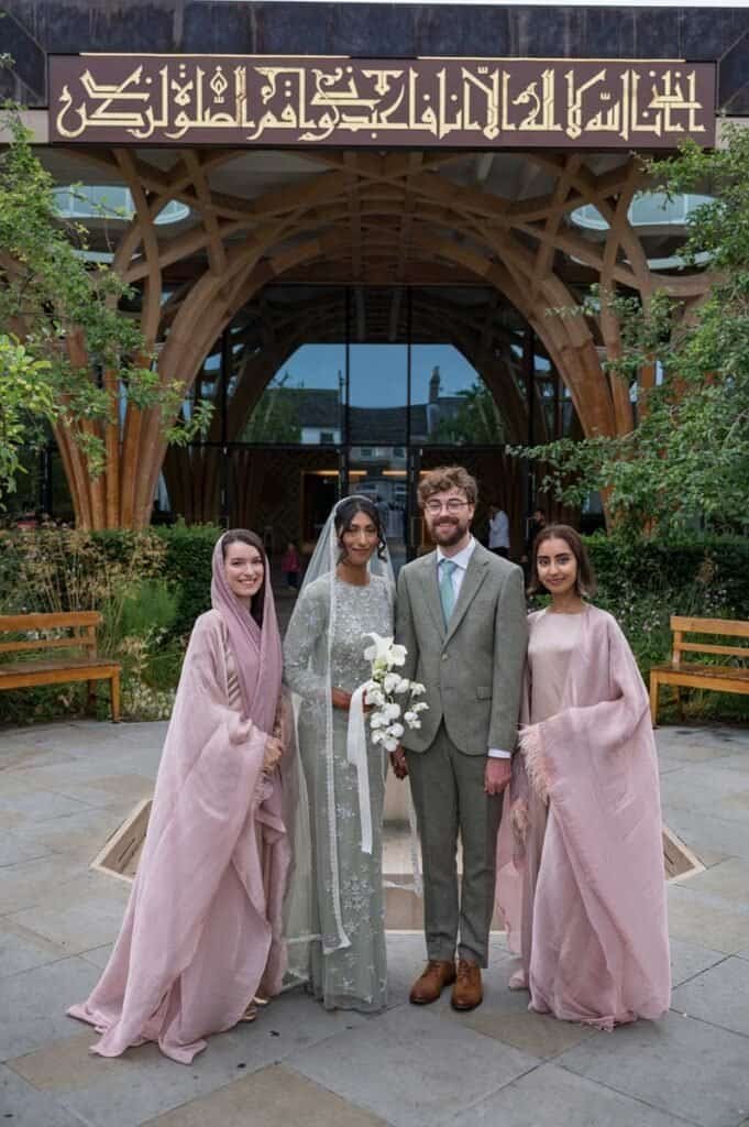 Bride and groom with two bridesmaids outside cambridge wedding venue.