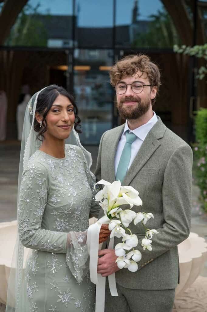 Beautiful bride and groom at wedding in cambridge with flowers and stylish attire.