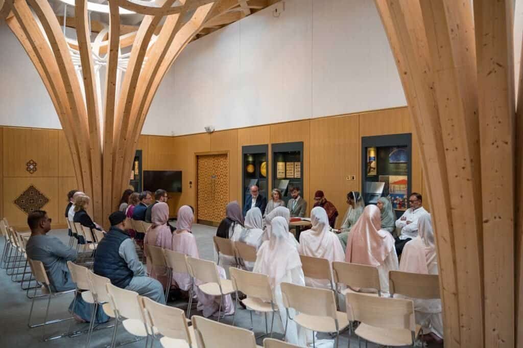 Group of diverse people attending a presentation in a modern wooden auditorium.